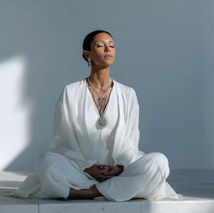 Person dressed in white meditating in a calm minimalist space, representing inner peace and alignment.
