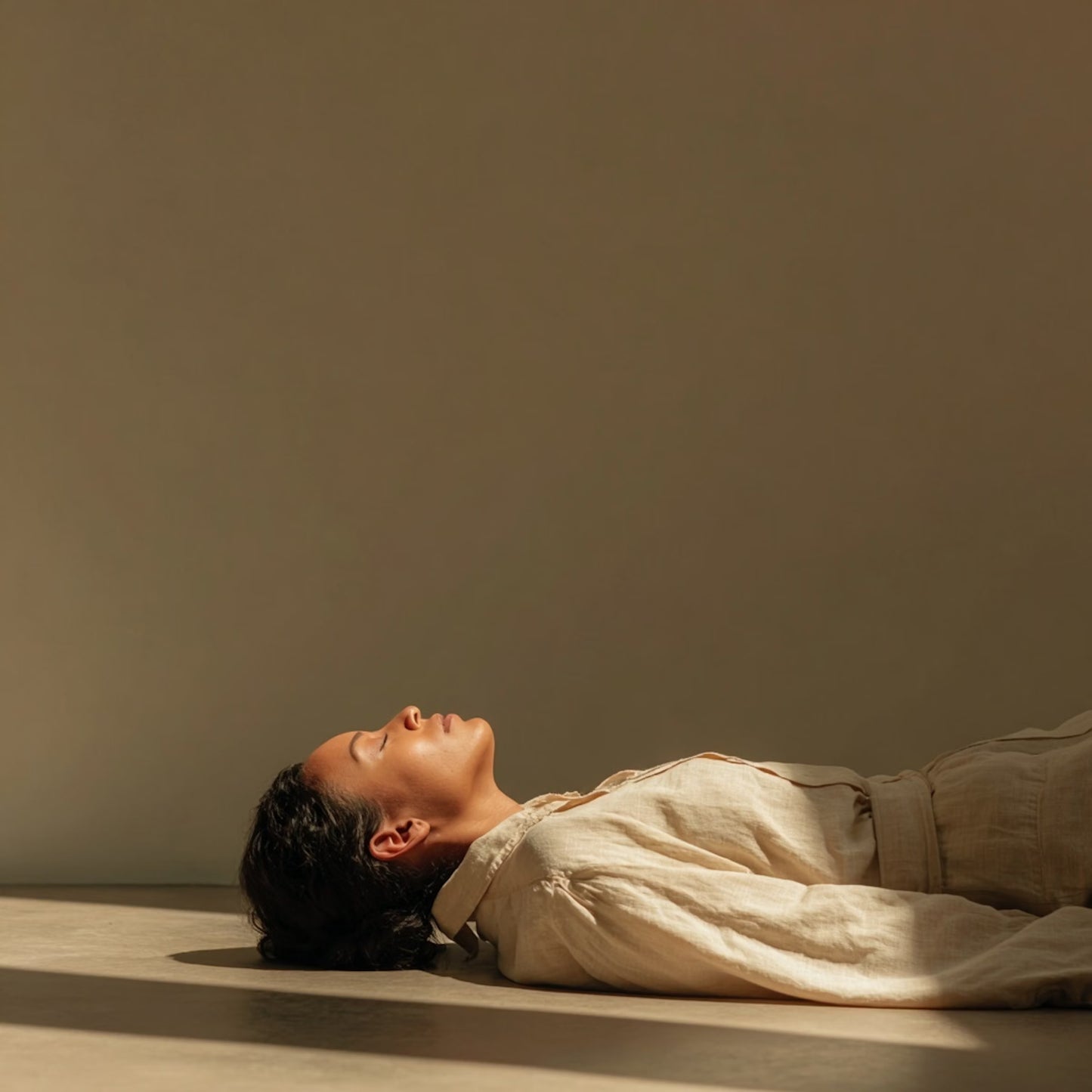Person lying on a mat in soft lighting, eyes closed in deep breathwork session.