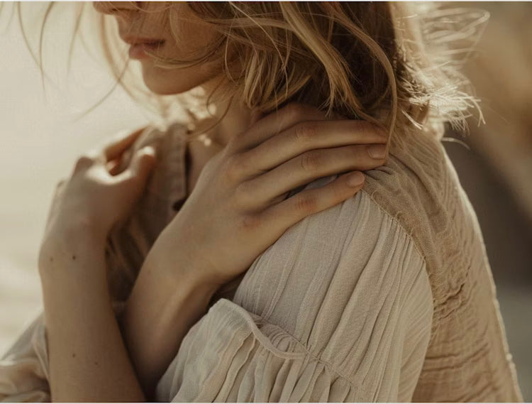 Person resting hands on their shoulders in self-soothing posture, symbolizing nervous system healing.