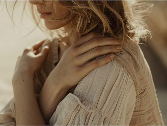 Person resting hands on their shoulders in self-soothing posture, symbolizing nervous system healing.